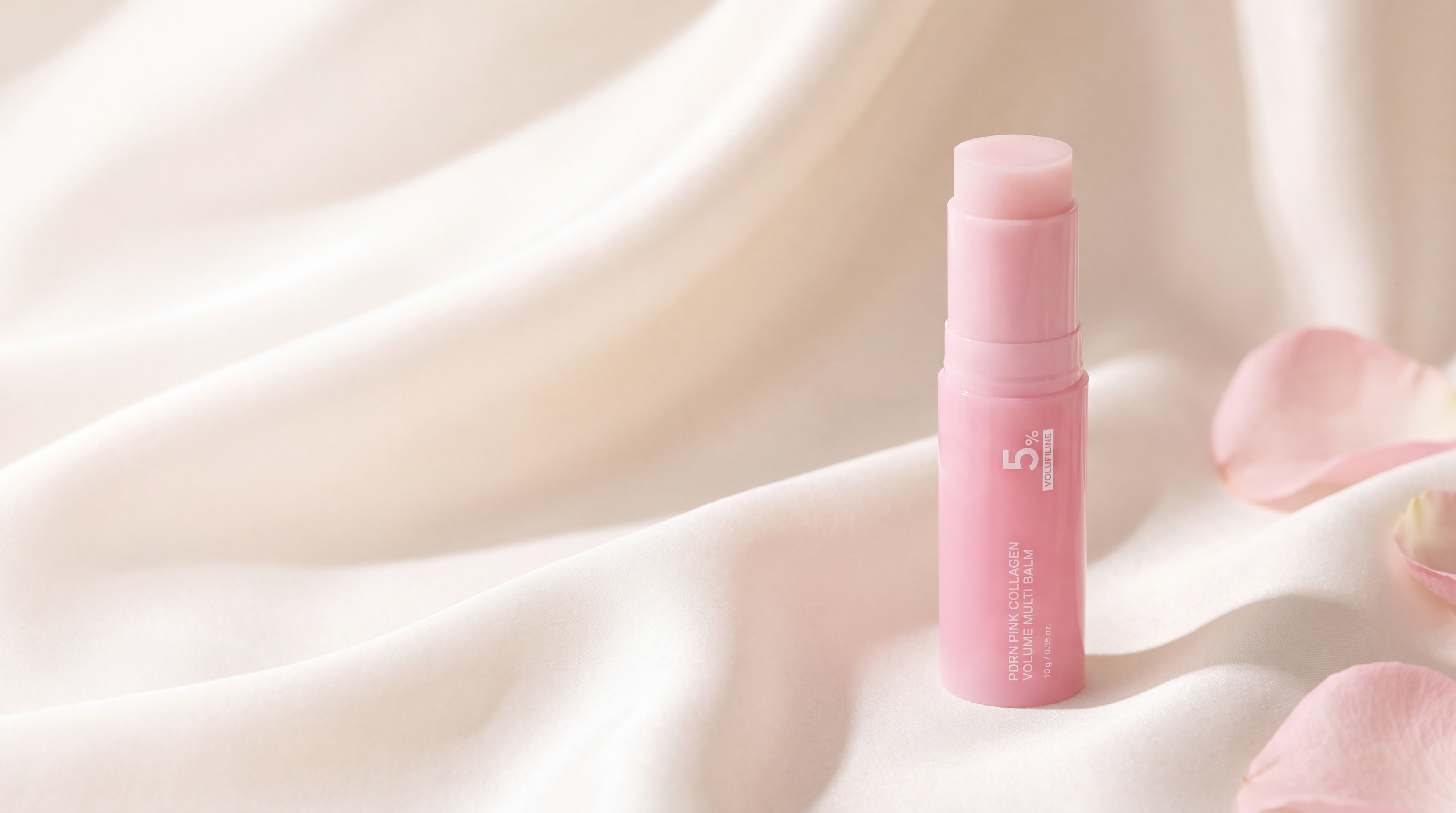 Aurelly Collagen Glow Multi-Balm standing uncapped on ivory silk with rose petals